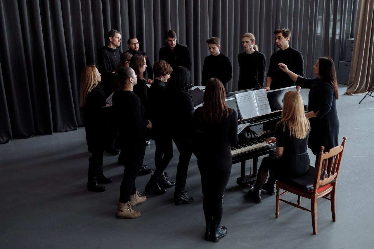 A choir group rehearsing indoors with a conductor and pianist, creating a musical harmony.